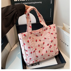 Dettaglio della borsa tote in velluto rosa con motivi a fragola rossa e trama morbida