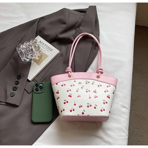 Detail of pink and white bucket bag featuring sweet cherry print and leather texture