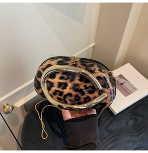 Detail of trendy leopard print shoulder bag with gold oval handle and chain strap on blue stool