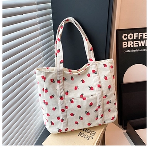 Primo piano della stampa fragola su borsa tote in velluto a coste bianco con manici