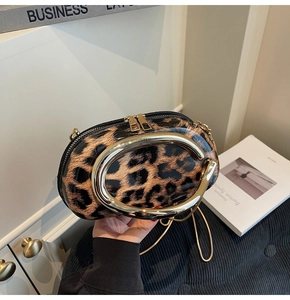 Detail of leopard print patent leather bag with a gold C-shaped handle and chain strap