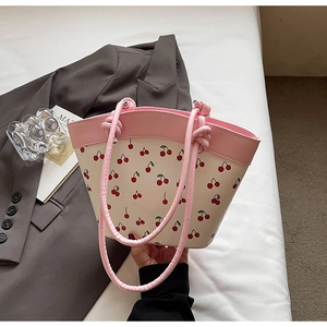 Detail of cherry print tote bag with pink knotted handles and smooth cream faux leather
