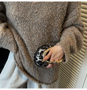 Detail of leopard print handbag with bold gold circular handle and fine metal chain strap
