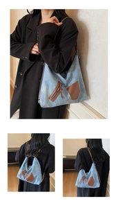 Detail of blue denim tote bag featuring brown leather trim and zipper pocket details