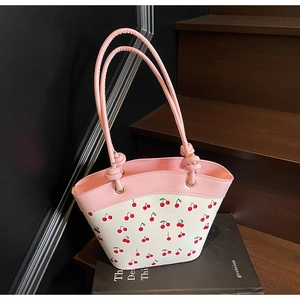 Close-up of pink and white cherry print tote bag with knotted handles on dark steps
