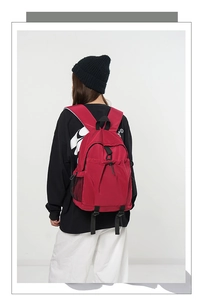 Detailed view of red backpack featuring durable checkered fabric and side mesh pocket