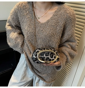 Detail of leopard print mini bag with gold C-handle and chain strap on a brown sweater