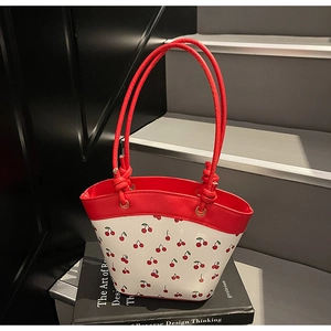 Detailed view of bucket bag with cherry print and red contrast stitching detail