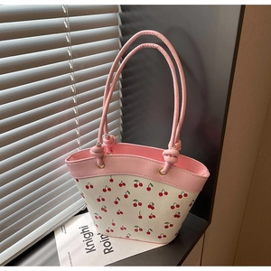 Close-up of pink and white bucket bag featuring cherry patterns and knotted strap detail