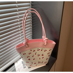Detail of pink handle and cherry print pattern on the white PU leather bucket bag