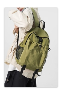 Detail of olive green nylon backpack with checkered texture and side mesh pocket