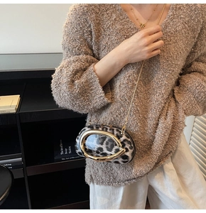 Close-up of leopard print crossbody bag with gold horseshoe handle and chain strap