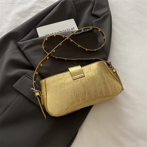 Chic gold crocodile pattern shoulder bag with eyelet strap on a stylish blazer background