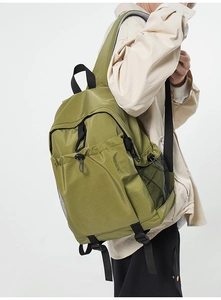 Side view of green ripstop backpack with mesh pockets and bungee cord on a model