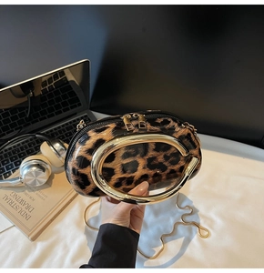 Detail of leopard print round bag featuring high-gloss finish and gold metal ring handle