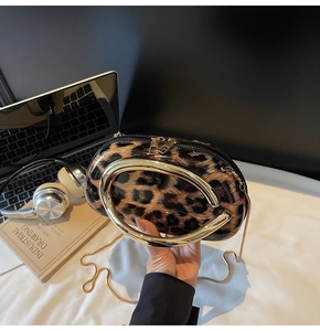 Detail of leopard print patent leather bag with gold ring handle and metal chain