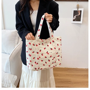 Close-up of corduroy tote bag featuring red strawberry print and soft texture