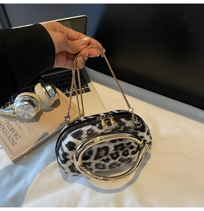 Detail of leopard print handbag with large gold metal handles and chain strap