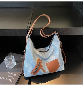 Detail of light blue denim tote bag with brown leather accents on wooden background