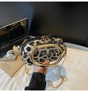 Detail of black and white leopard print bag with gold C-handle and chain strap