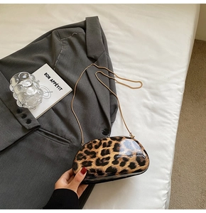 Detail of leopard print crossbody bag with glossy finish and elegant gold chain strap