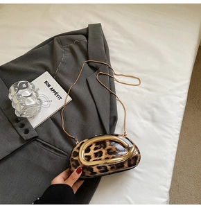 Detail of leopard print crossbody bag with gold metal handle on a grey blazer