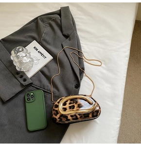 Chic leopard print bag with gold horseshoe handle styled on a grey blazer suit