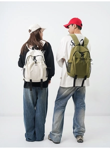 Dual view of cream and olive green nylon backpacks showing wide padded shoulder straps