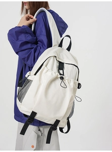 Detail view of large white backpack with side mesh pocket and adjustable black buckle strap