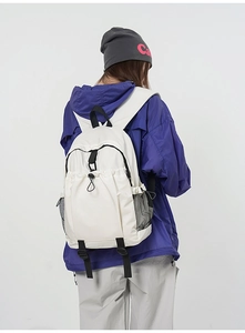 Detail of white nylon backpack featuring ergonomic straps and black mesh side pockets