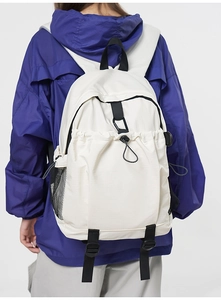 Rear view of a white minimalist backpack with black straps and bungee cords on model