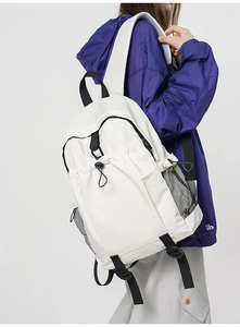 Detail of white nylon backpack featuring side mesh pockets and adjustable drawstrings