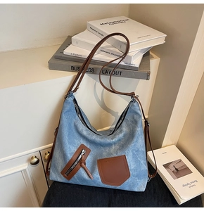 Detail of blue canvas hobo bag with brown leather pockets and metal zipper closure