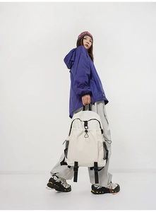 Detailed view of beige backpack featuring drawstring closure and side mesh pockets