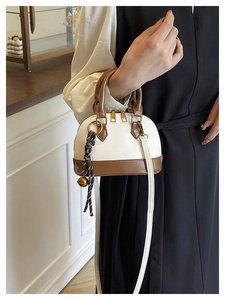 Détail d'un sac bandoulière vintage en forme de coquille crème et marron avec breloque