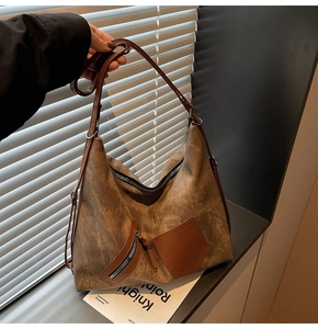 Detail of vintage brown textured hobo bag featuring dark leather pocket and shoulder strap