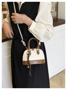 Model wearing a retro bicolor shell bag with crocodile texture and woven pendant