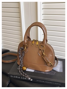 Détail d'un sac bandoulière marron en cuir lisse avec pendentif clochette élégant