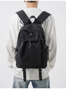 Close-up of black nylon backpack featuring drawstring pocket and breathable mesh side pocket