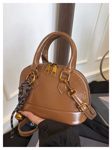 Détail d'un sac à main en cuir marron avec fermeture éclair dorée et bijou de sac