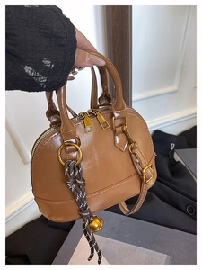 Détail d'un sac coquille marron en cuir PU brillant avec clochette dorée élégante