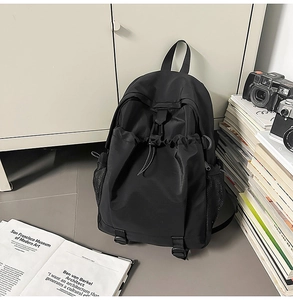 Detailed view of black nylon backpack with drawstring front pocket and mesh side storage