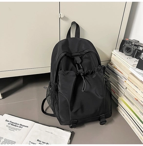 Close-up of black nylon backpack with drawstring front pocket and functional metal buckle