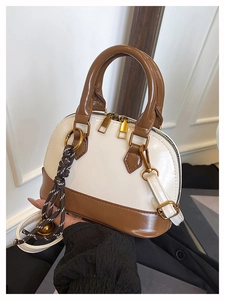 Détail d'un sac à main bicolore en forme de coquillage avec poignées contrastées
