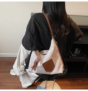 Detail view of large commuter tote bag featuring dark brown leather straps and zip pocket