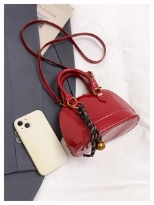 Détail du mini sac coquille rouge brillant avec accessoire de clochette tressée unique