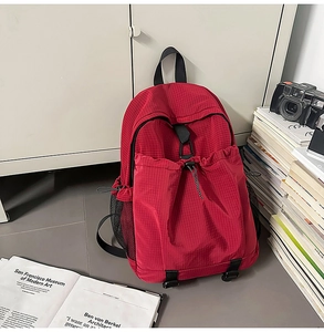 Detail of red checkered nylon backpack with drawstring pocket and black mesh side pocket
