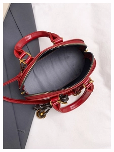 Détail du sac bandoulière en cuir verni rouge montrant la doublure et la fermeture