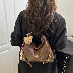 Sac fourre-tout vintage en cuir marron avec breloque ours et ruban, porté à l'épaule