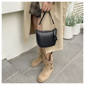 Detail of black matte saddle bag with gold zippers and fashion embossing on a model